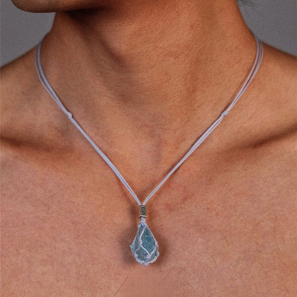 Aquamarine hand-woven cord necklace featuring a vibrant blue gemstone pendant on a natural cord, displayed against a neutral background.