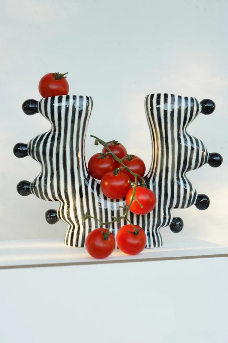 Black and white striped ceramic wall art with tomatoes on a white background