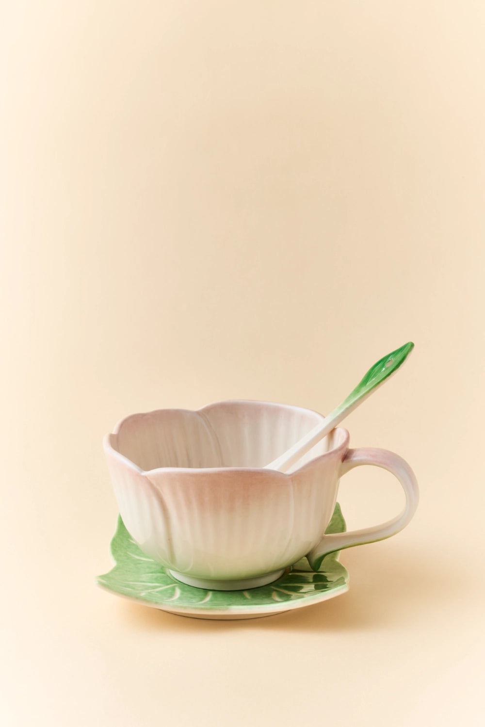 Pink ceramic Begonia cup and saucer set with matching spoon, elegant and decorative for tea or coffee presentation.