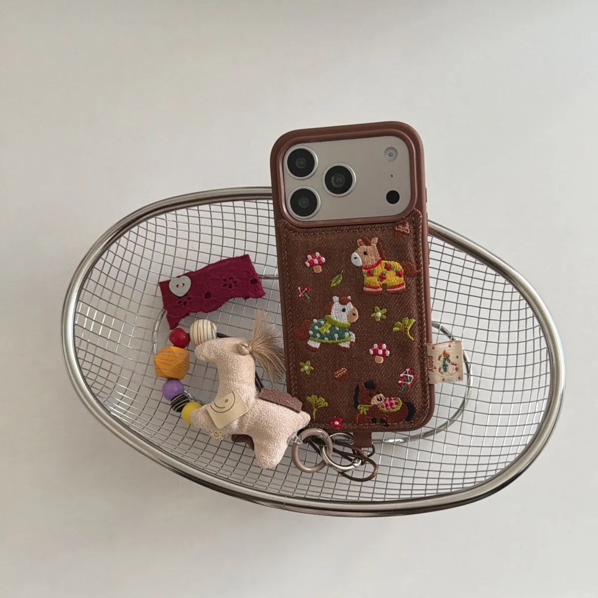 Embroidered pony design on TRLab Shop phone case, featuring colorful stitching and protective material for smartphone protection.
