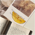 Translucent fruit-shaped acrylic bookmark with colorful fruit illustrations, ideal for marking pages in books.