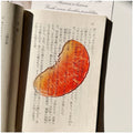Translucent fruit-shaped acrylic bookmark with colorful fruit illustrations, ideal for marking pages in books.