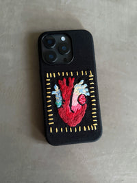 Embossed heart embroidery on TRLab Shop phone case, showing detailed stitched red heart design on a protective cover.