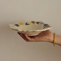 Hand-pinched ceramic plate featuring floral and bird motifs, crafted in coarse pottery by TRLab Shop.