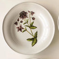 Decorative floral ceramic plate with vibrant flower patterns, designed by TRLab Shop, showcasing intricate botanical artwork on a round plate.